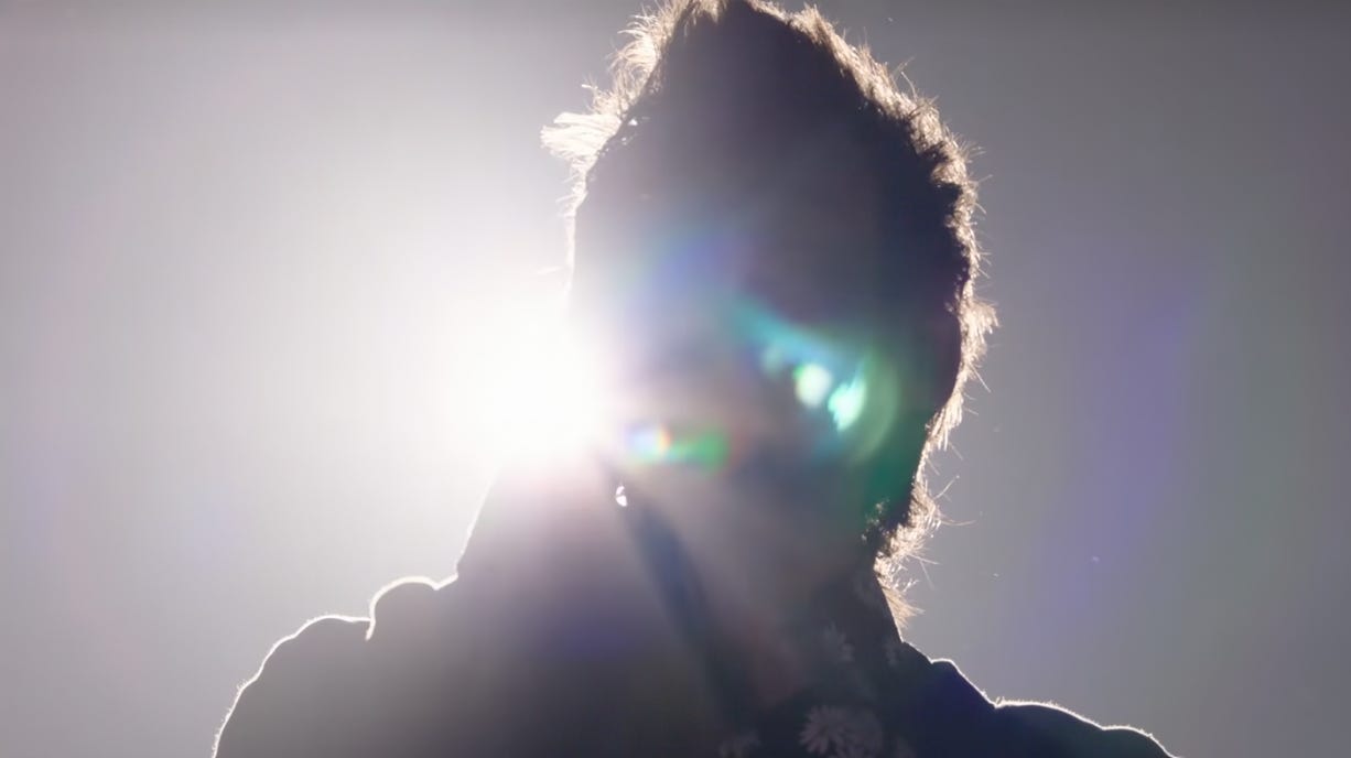 Harry Styles on stage during One Night In Manchester, silhouetted by stage lights.