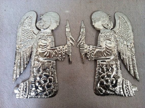 This may contain: two metal angel figurines sitting next to each other