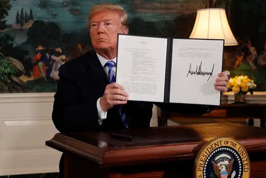 Donald Trump holds up a signed document while standing at a lectern