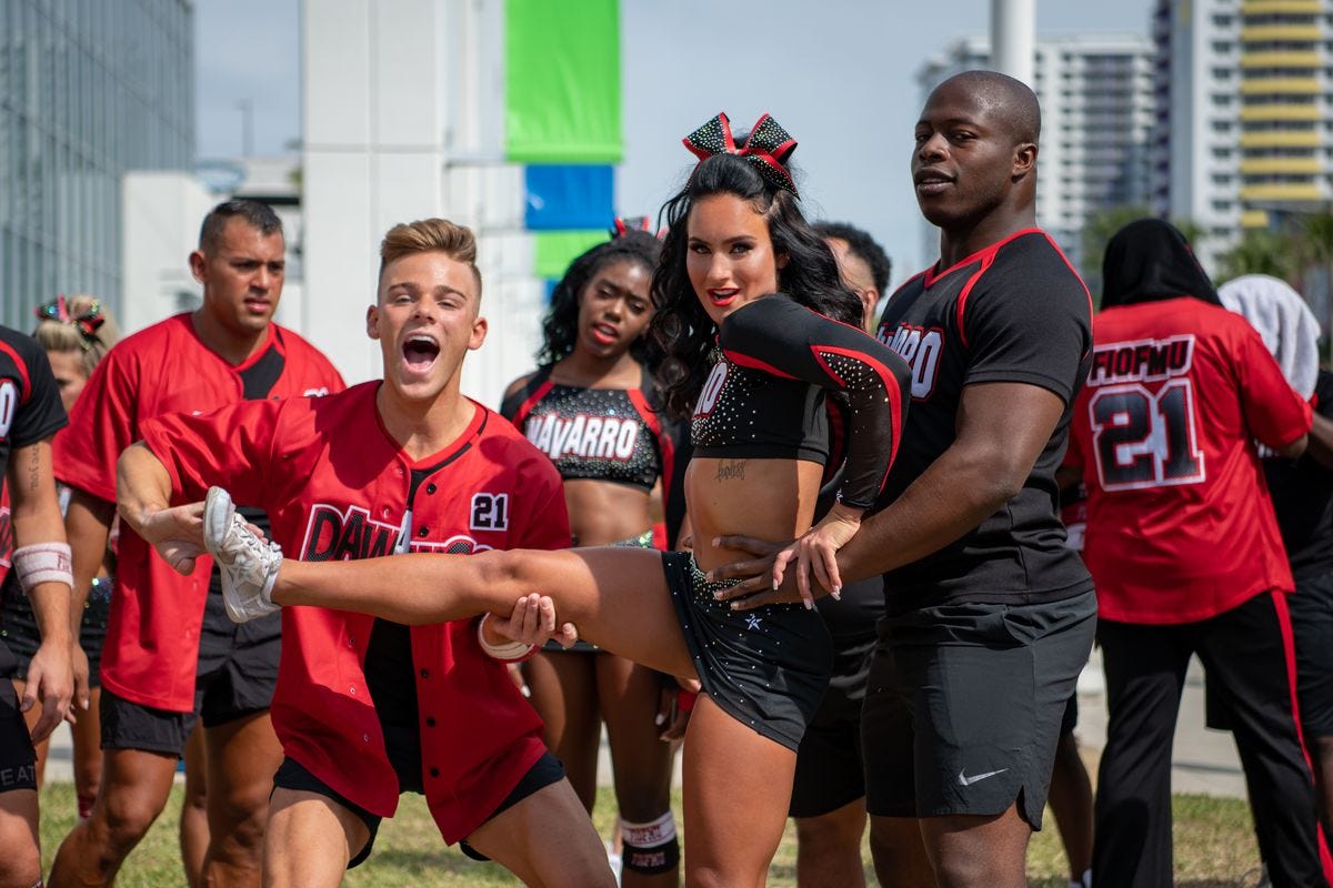 A cheer squad practices by trying to lift a cheerleader who is standing on one leg.
