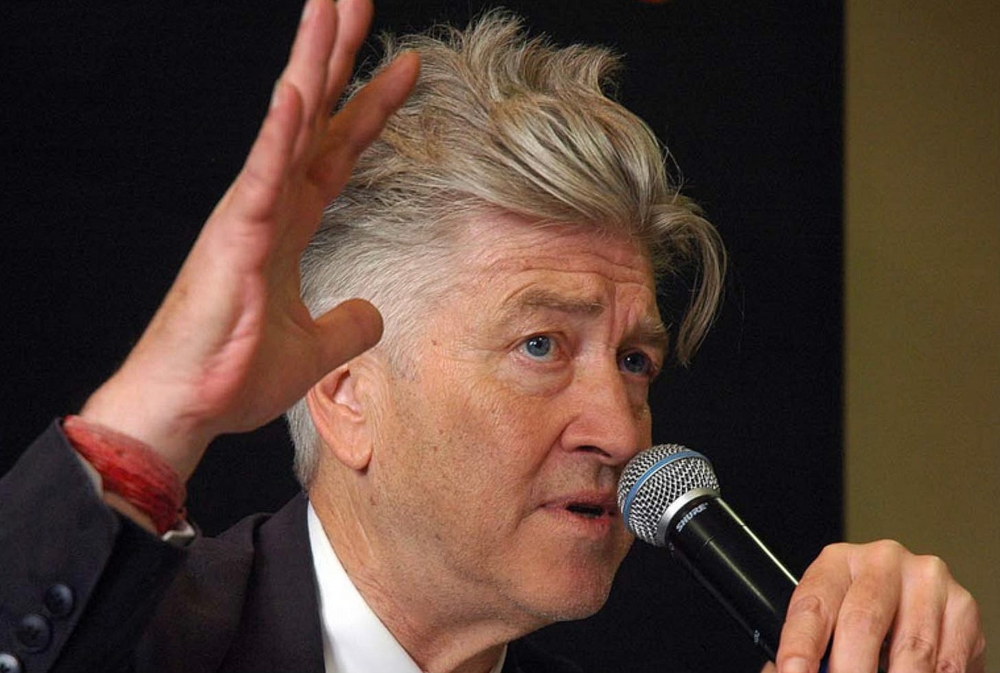 David Lynch speaking into a microphone at a press event