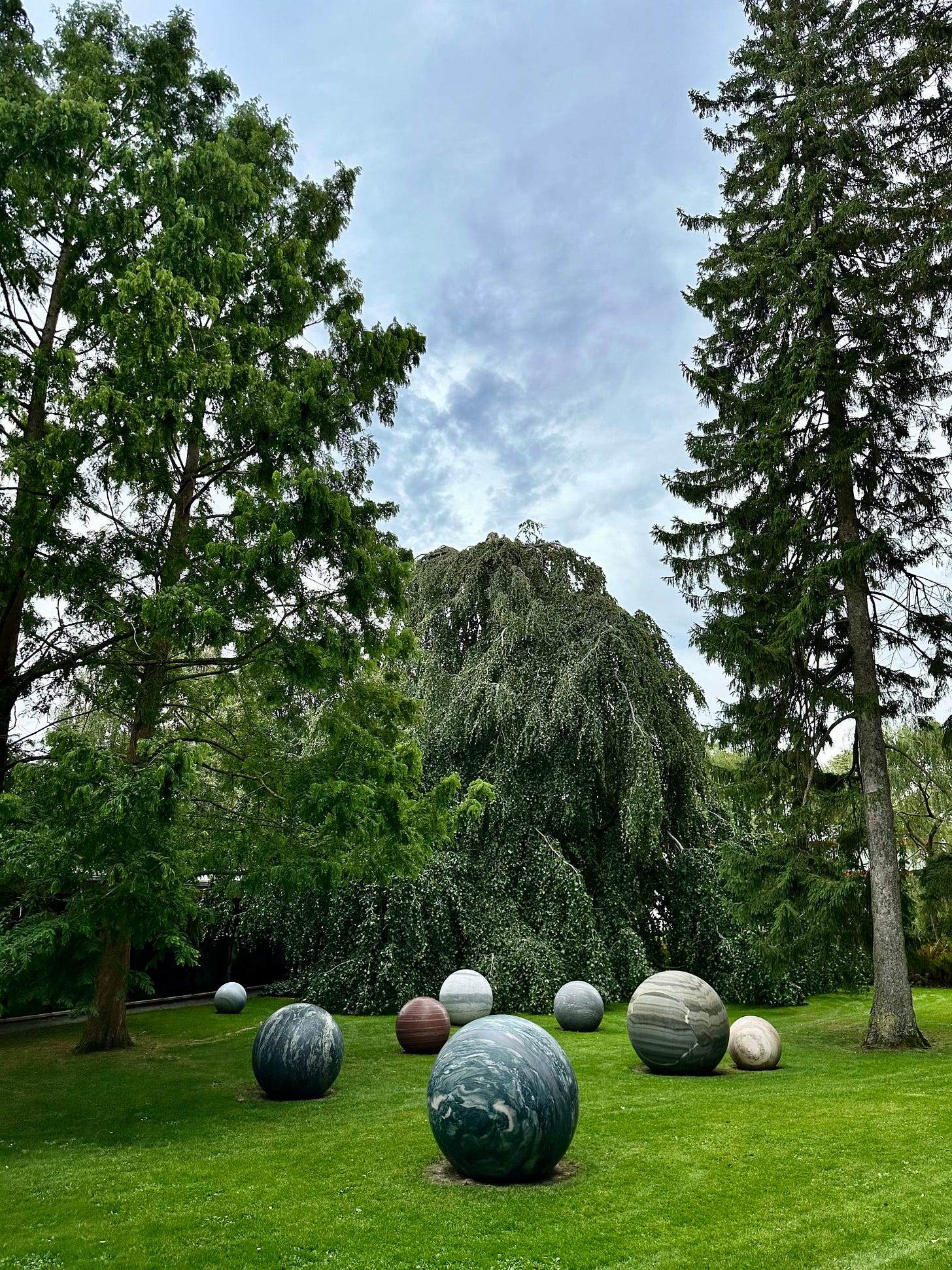 A woodland park which has a number of smooth spherical rocks on the ground that have a marbled texture to resemble stationery planets.