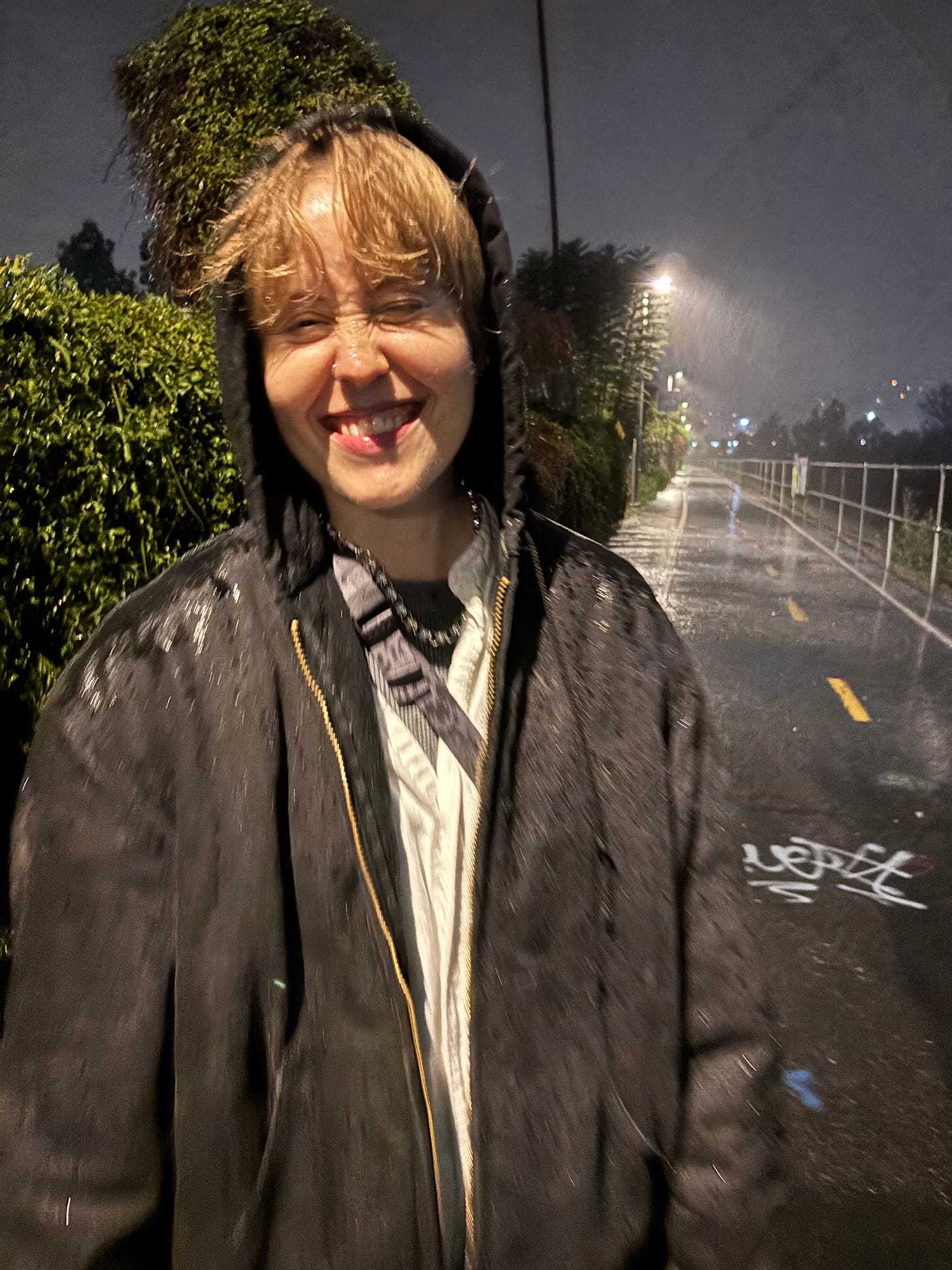 Fi stands on the LA river bike path in the middle of a downpour