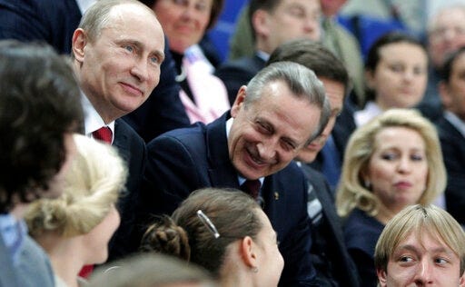 FILE - Russian Prime Minister Vladimir Putin, left, and President of the Russian figure skating federation Alexander Gorshkov, center, attend the pairs competition at the ISU Figure skating World championships in Moscow, April 27, 2011. Russian ice dancer Alexander Gorshkov has died at the age of 76, it was announced Thursday, Nov. 17, 2022. He won the first Olympic ice dance gold medal for the Soviet Union at the 1976 Games and later became a leading official in Russian figure skating.(AP Photo/RIA Novosti, Alexei Druzhinin, Pool, file)
