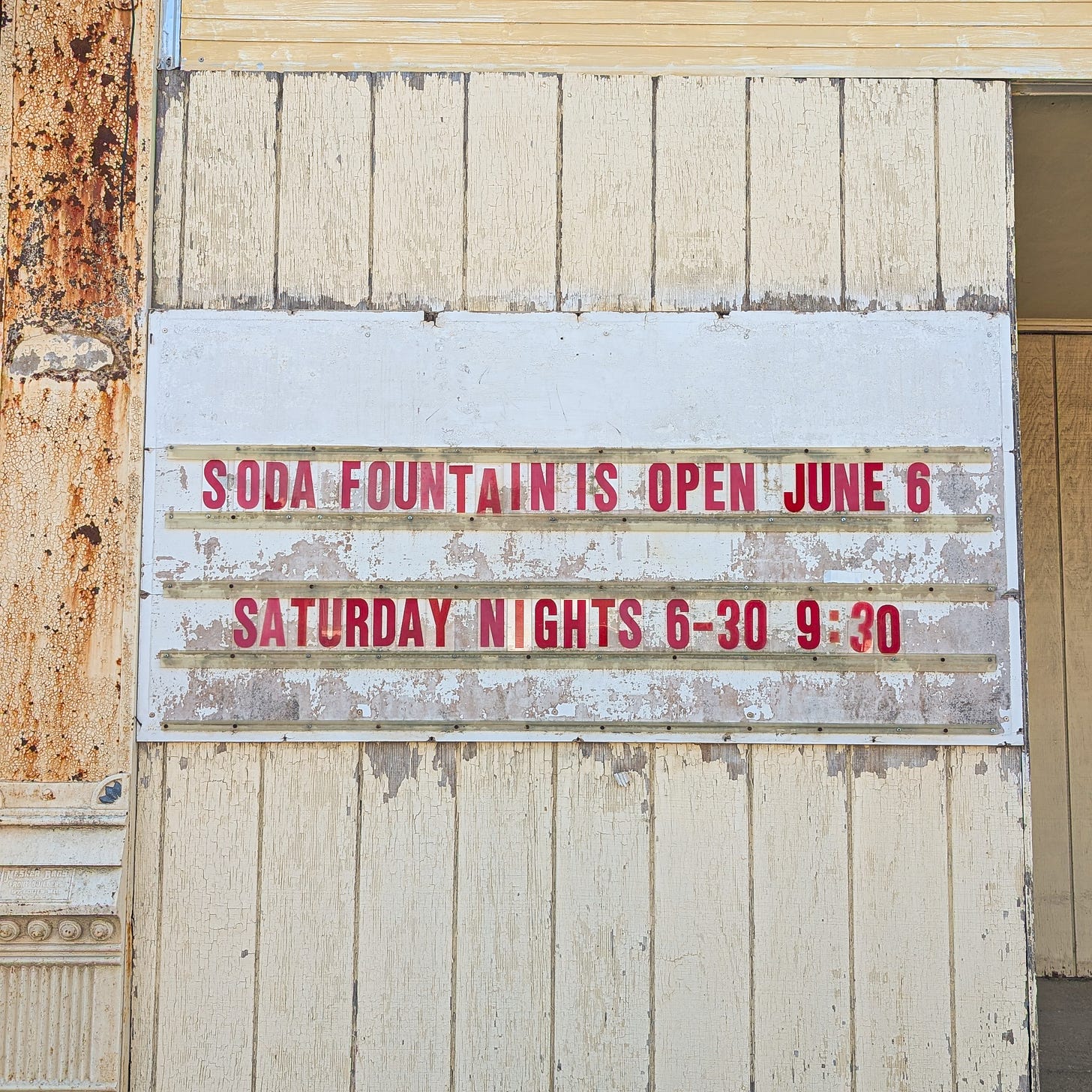 A faded sign with red lettering saying the soda fountain is open saturday nights 6:30-9:30