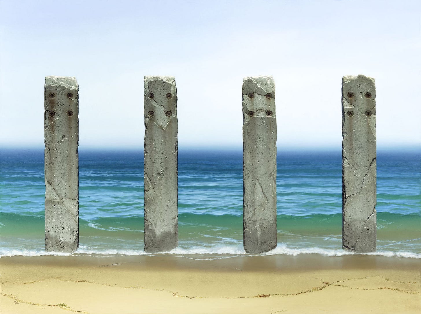 Four weathered pillars of concrete stand at ocean's edge. The sky is a hazy fog that blurs at the horizon above a deep blue sea. Approaching the foreground, sea green water becomes glassy reflecting the sun as the receding tide slowly rolls out depositing a meandering line of detritus on the wet sand. Four weathered pillars of concrete stand at ocean's edge. The sky is a hazy fog that blurs at the horizon above a deep blue sea. Approaching the foreground, sea green water becomes glassy reflecting the sun as the receding tide slowly rolls out depositing a meandering line of detritus on the wet sand.