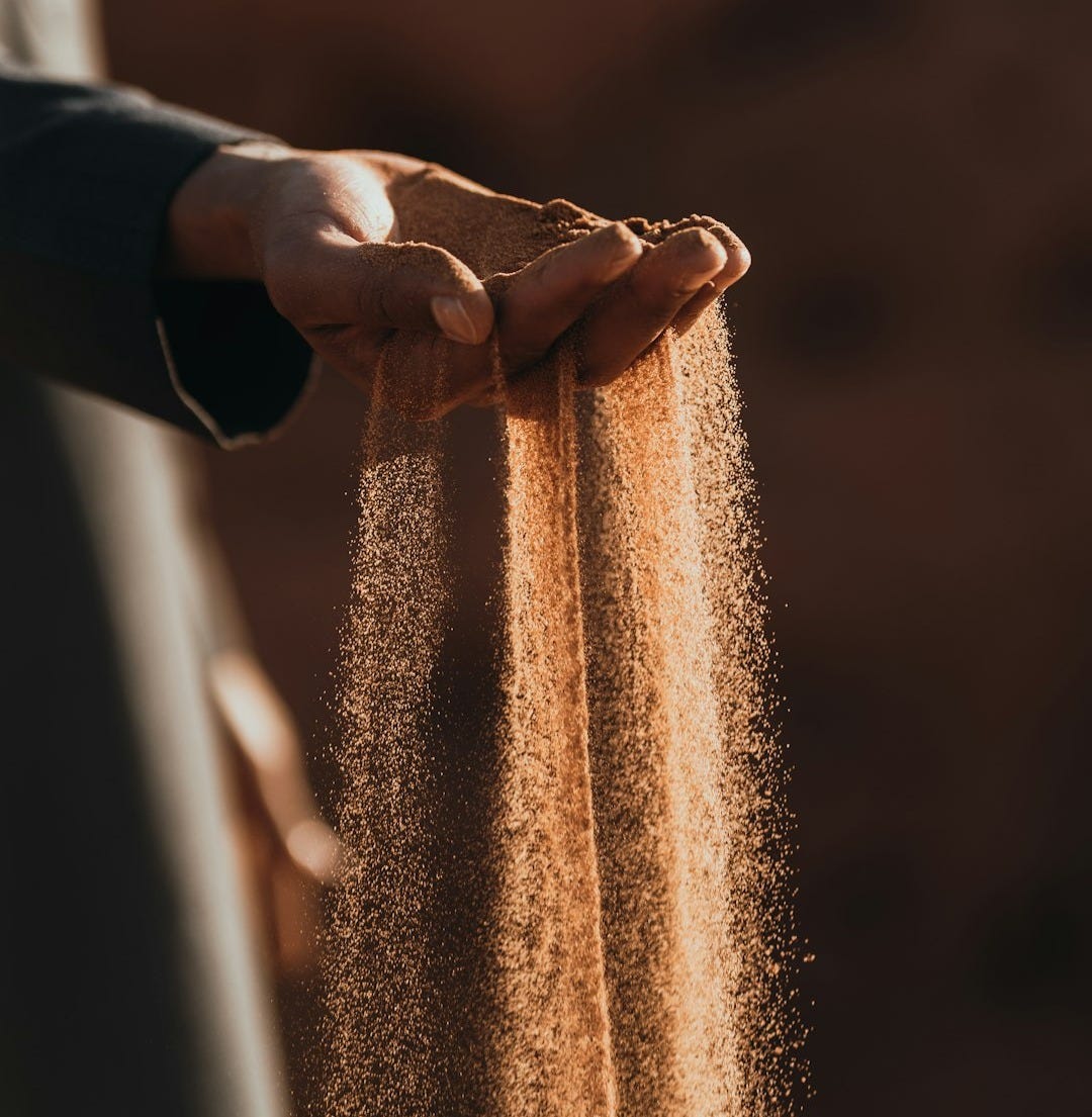 a person holding sand in their hands