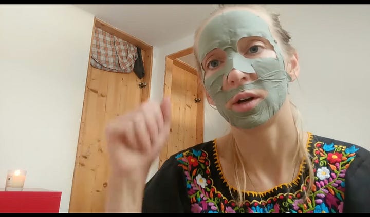 Primo piano su una persona che si trucca o applica ciglia finte sul suo occhio destro. Usa le dita e uno strumento nero per tenere ferma la palpebra e posizionare l'oggetto scuro vicino alla linea delle ciglia. La persona indossa una maglietta grigia, ha lunghe ciglia scure e un anello sottile con piccole pietre al dito medio della mano destra.