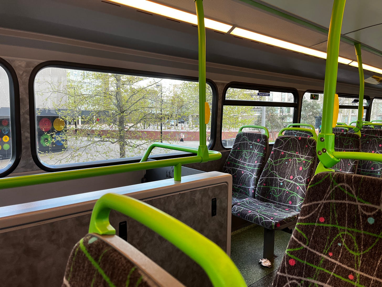 Photo of the upper floor of a StreetDeck bus showing seat moquette, handlebars, lighting.