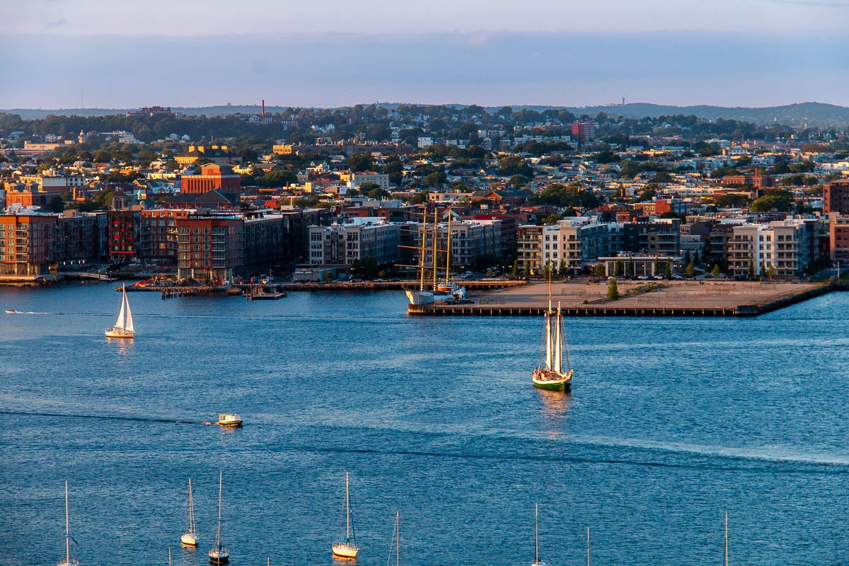 View of Boston Harbor facing East Boston with two sailboats and masts of many others.