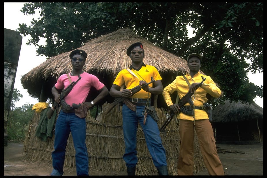 Men stand holding their weapons, wearing sunglasses and berets Men stand holding their weapons, wearing sunglasses and berets