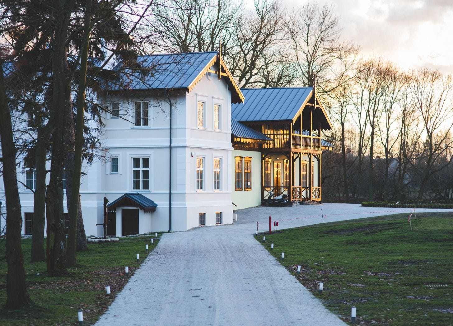 A quiet lodging property at dusk with a clear driveway leading to warmly lit buildings, signaling a calm and predictable arrival.
