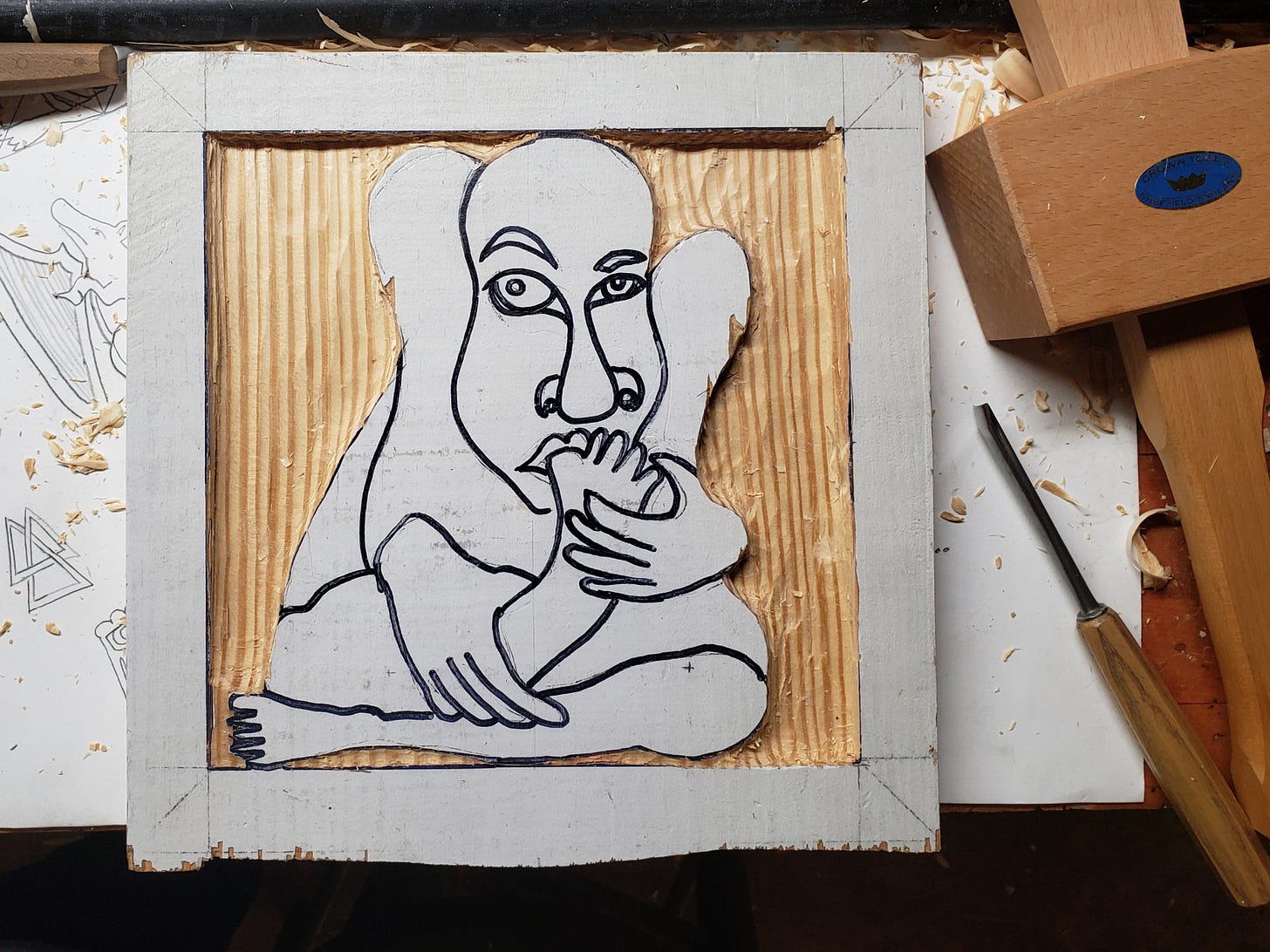 beginning stage relief wood carving with man with foot in mouth