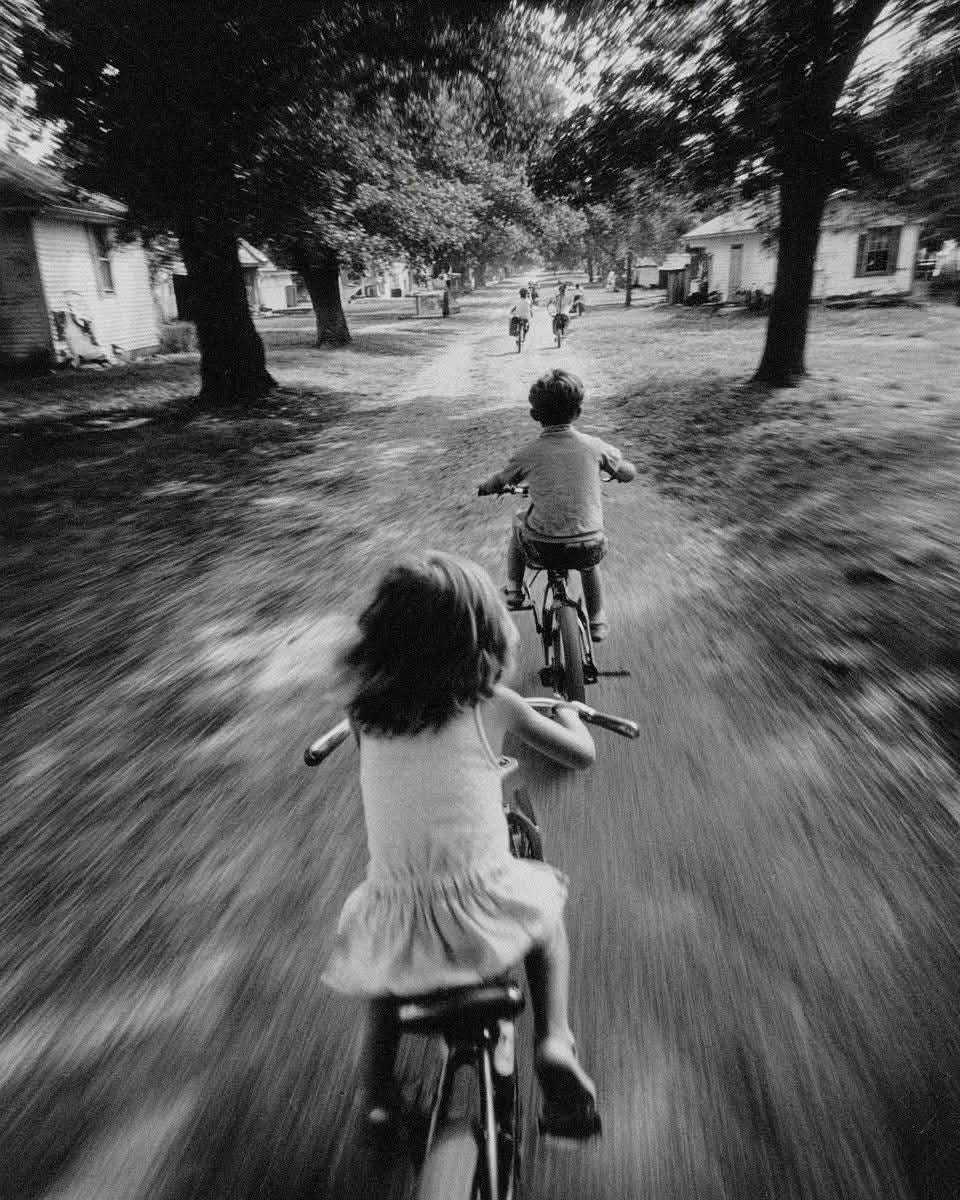 May be a black-and-white image of child and bicycle