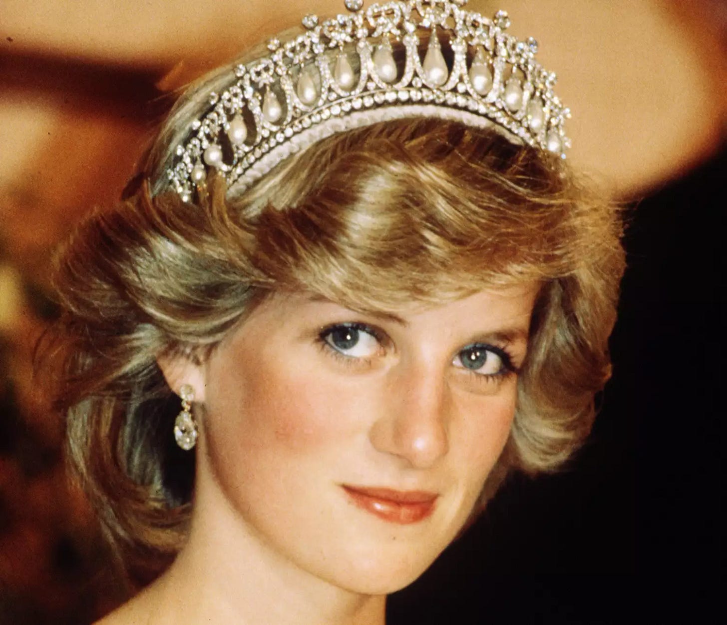 Diana, Princess of Wales, wearing a cream satin dress by Gina Fratini with the Queen Mary Cambridge Lover's Knot Tiara and diamond earrings attends a banquet on April 29, 1983 in Auckland, New Zealand Diana, Princess of Wales, wearing a cream satin dress by Gina Fratini with the Queen Mary Cambridge Lover's Knot Tiara and diamond earrings attends a banquet on April 29, 1983 in Auckland, New Zealand