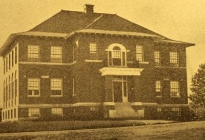 A large brick building with a large front door

AI-generated content may be incorrect.