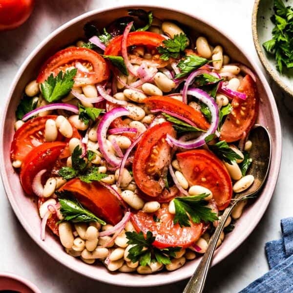 Piyaz - Turkish White Bean Salad in a bowl with a spoon on the side from top view.