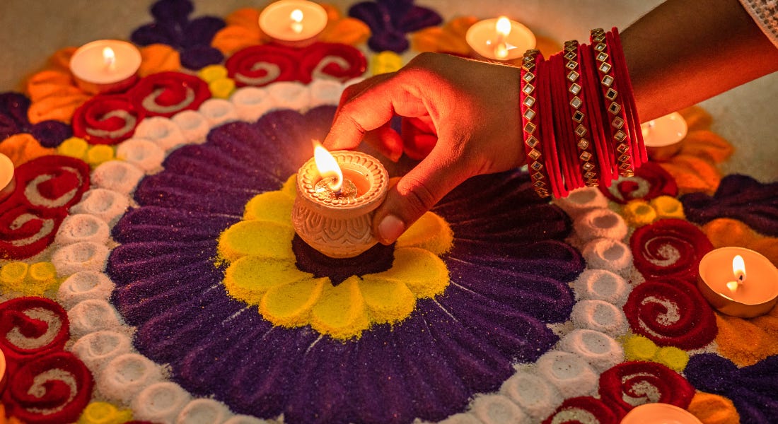 A candle being placed in the middle of purple, yellow, white, and red swirly sand A candle being placed in the middle of purple, yellow, white, and red swirly sand