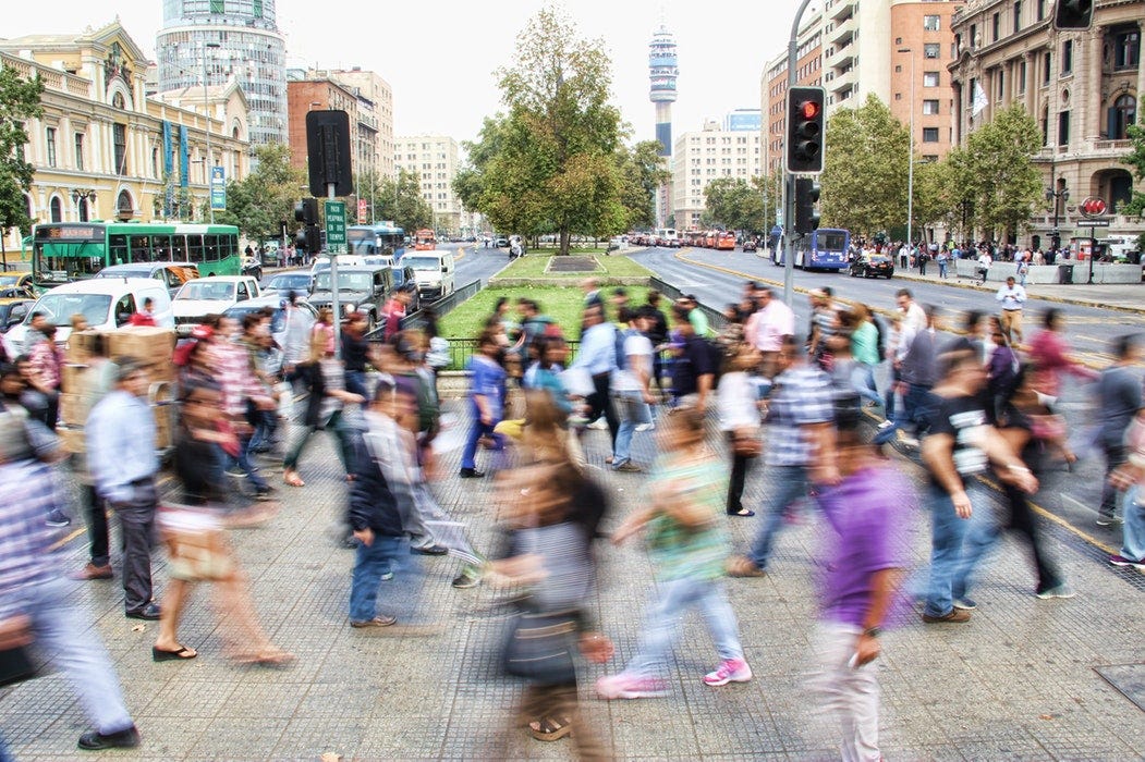 Many busy people crossing a street