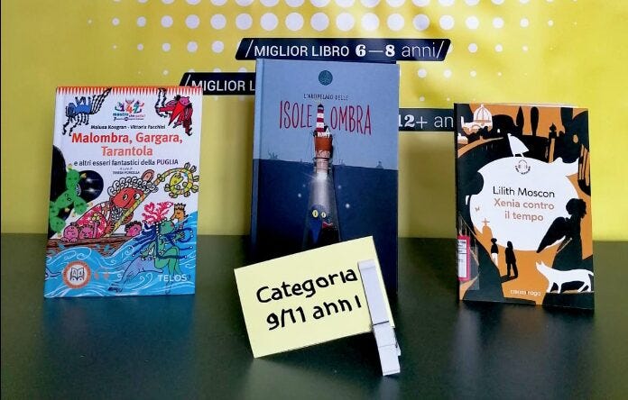 Tre libri appoggiati su un tavolo verde e lo sfondo giallo. In primo piano la scritta "Categoria 9/11 anni". I titoli dei tre libri, da sinistra a destra sono: Malombra, Gargara, Tarantola. L'arcipelago delle isoleombra. Xenia contro il tempo.