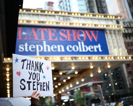 TOPSHOT-US-POLITICS-MEDIA-COLBERT-TRUMPTOPSHOT - People hold signs supporting Stephen Colbert outside the Ed Sullivan Theater ahead of the taping of the final episode of the "The Late Show" after 32 years on air, in New York, on May 21, 2026. "The Late Show" frontman Stephen Colbert will host the final edition of the 33-year-old US cultural institution on May 21, after it was cancelled by CBS as the network courted President Donald Trump. The show, which Colbert has hosted since 2015, was axed after he mocked the broadcaster for a $16 million settlement with Trump for allegedly "maliciously" editing an interview with his Democratic election rival Kamala Harris. (Photo by CHARLY TRIBALLEAU / AFP via Getty Images)