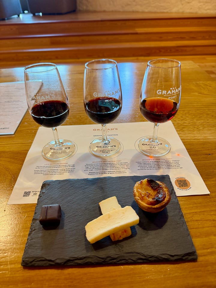 A port wine tasting flight of three glasses at Graham's port house in Vila Nova de Gaia, Porto, with chocolate, cheese, and a pastel de nata on a slate board