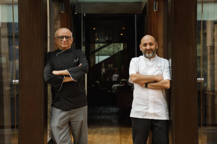 Chefs Sameer Taneja and Shantanu Mehrotra posing in front of a restaurant door