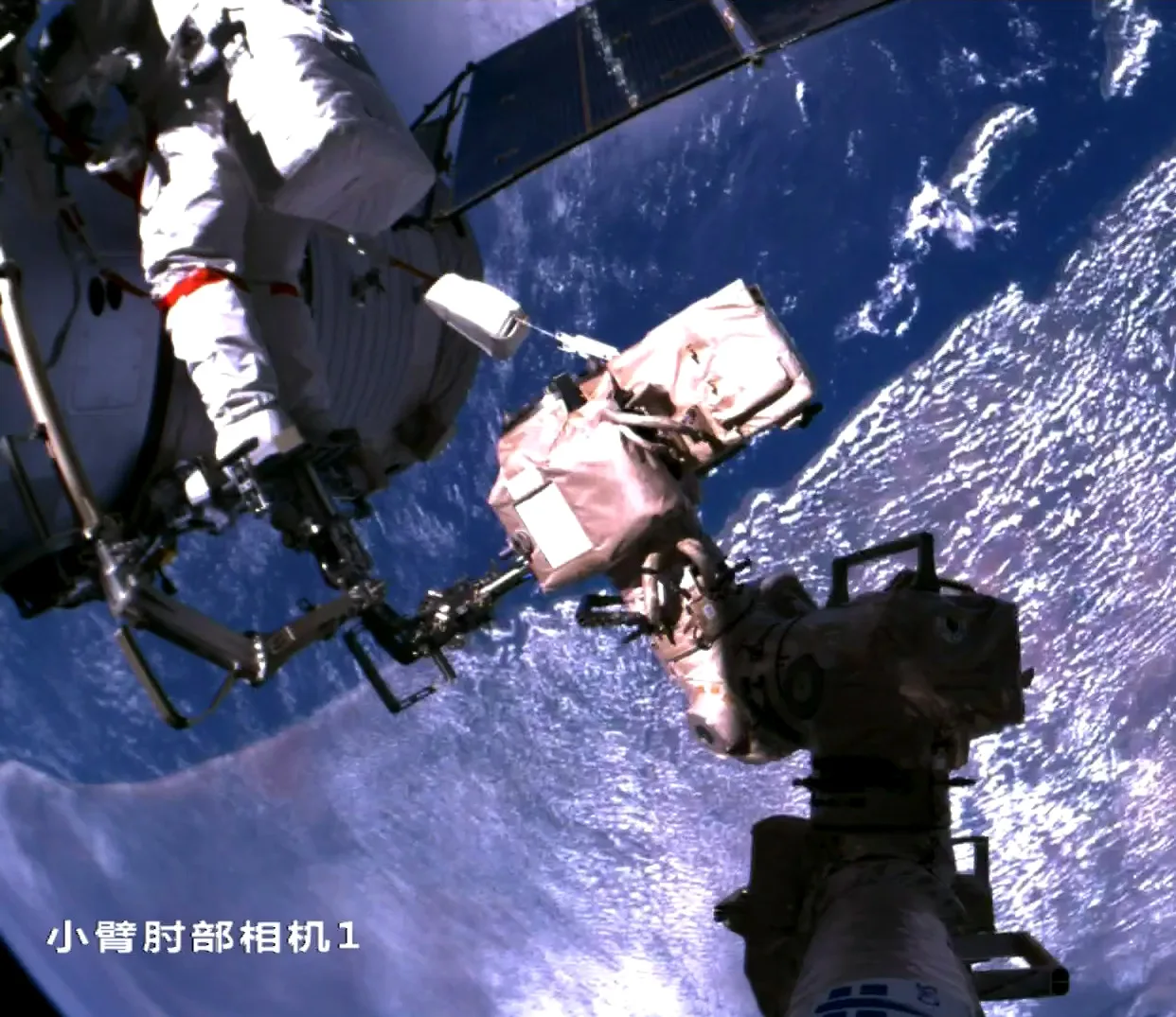 Zhang Lu sul braccio robotico della Tiangong per ispezionare la capsula Shenzhou-20 dall'esterno, il 9 dicembre 2025.