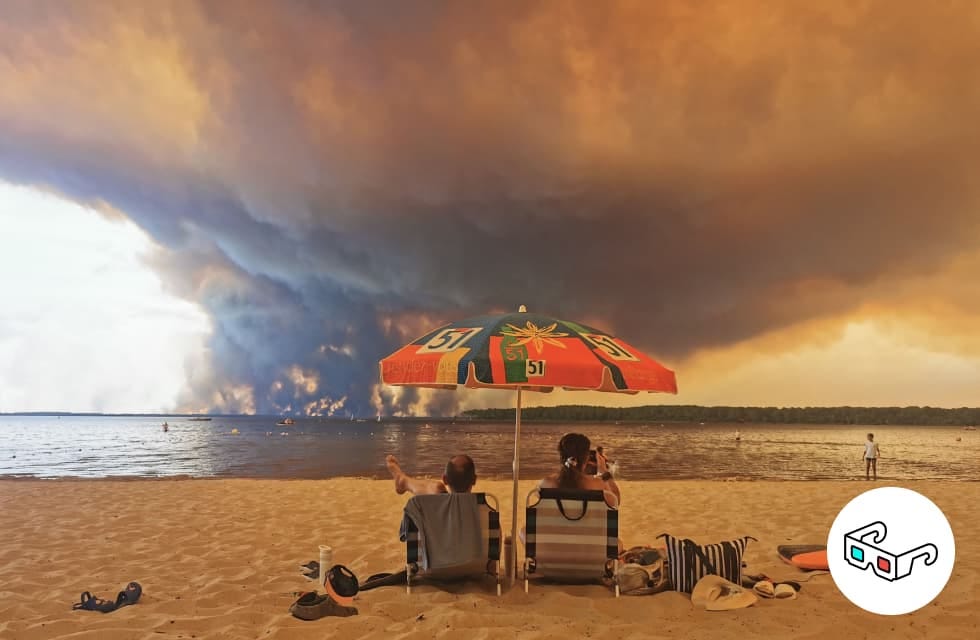 Vacanciers installés sous un parasol, sur la plage, alors qu’à l’horizon, le feu dévore la forêt en Gironde, à l’été 2026 - photo Maximilien Lamy Vacanciers installés sous un parasol, sur la plage, alors qu’à l’horizon, le feu dévore la forêt en Gironde, à l’été 2026 - photo Maximilien Lamy