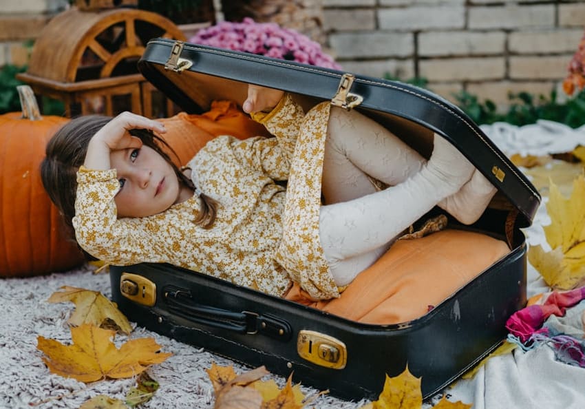 A small girl hiding in a suitcase