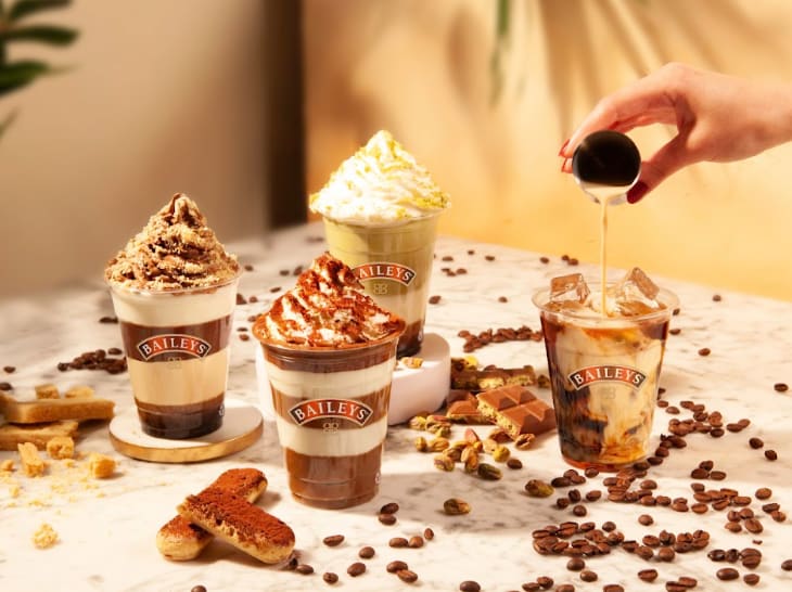 Four drinks in Baileys branded glasses, topped with whipped cream and various toppings