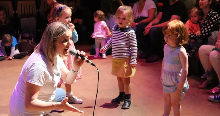 A woman singing to toddlers