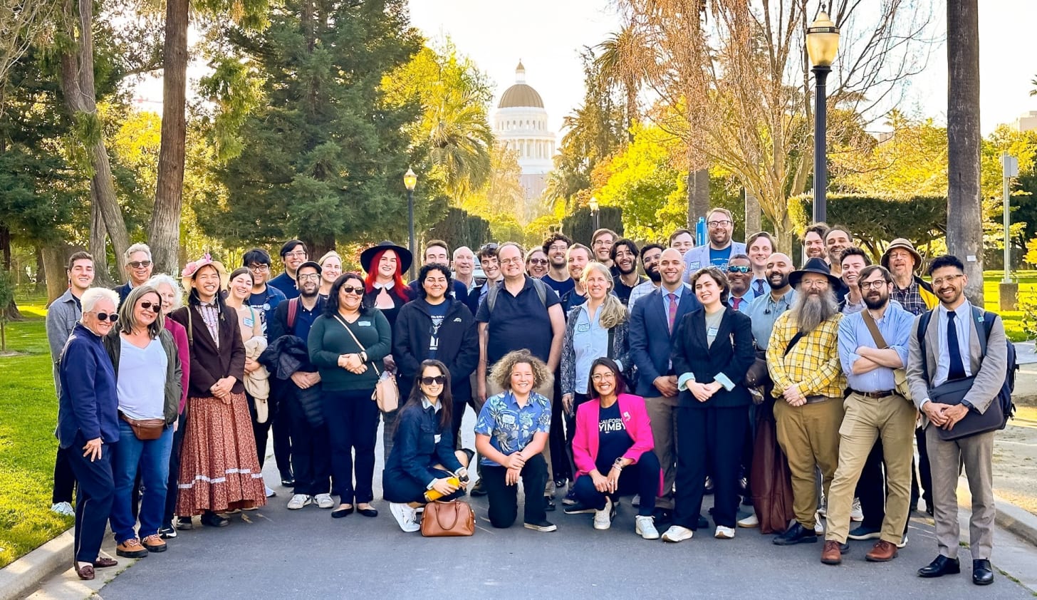 A large group of YIMBY activists standing in front of the California capitol building.