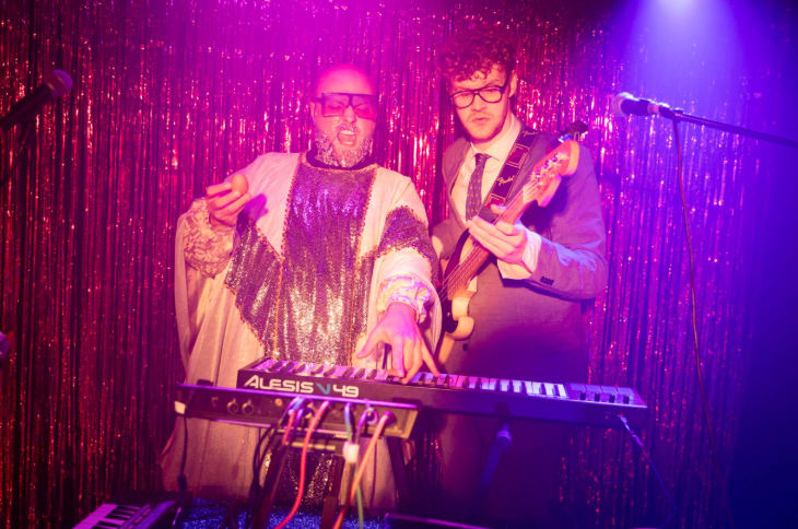 Two people on stage performing with a keyboard and guitar