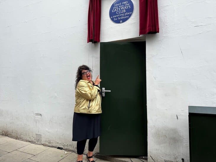 A blue plaque being unveiled above a green door