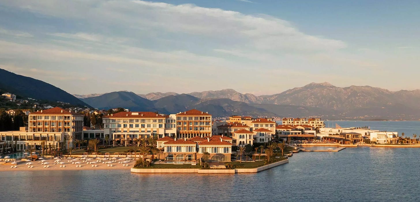 Aerial view of One&Only Portonovi resort along the Boka Bay coastline in Montenegro at golden hour, with terracotta rooftops, palm-lined grounds, and dramatic mountains in the background