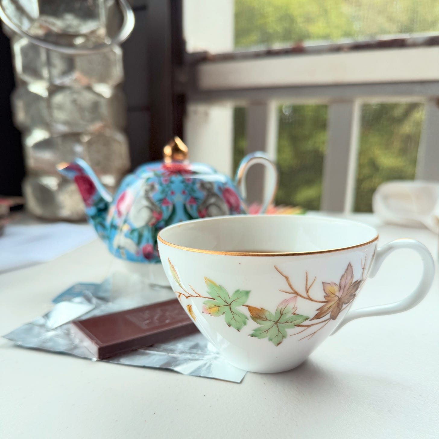 swirling leaves teacup with chocolate and teapot
