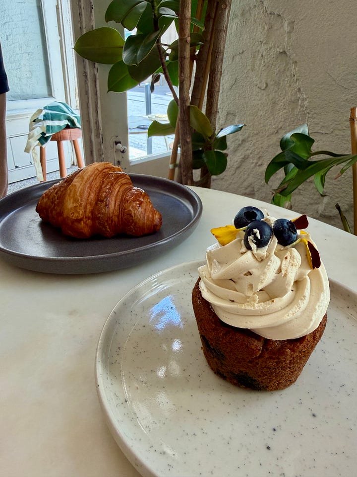 A croissant and a frosted pastry topped with blueberries and edible flowers at Audrey's restaurant in Lisbon