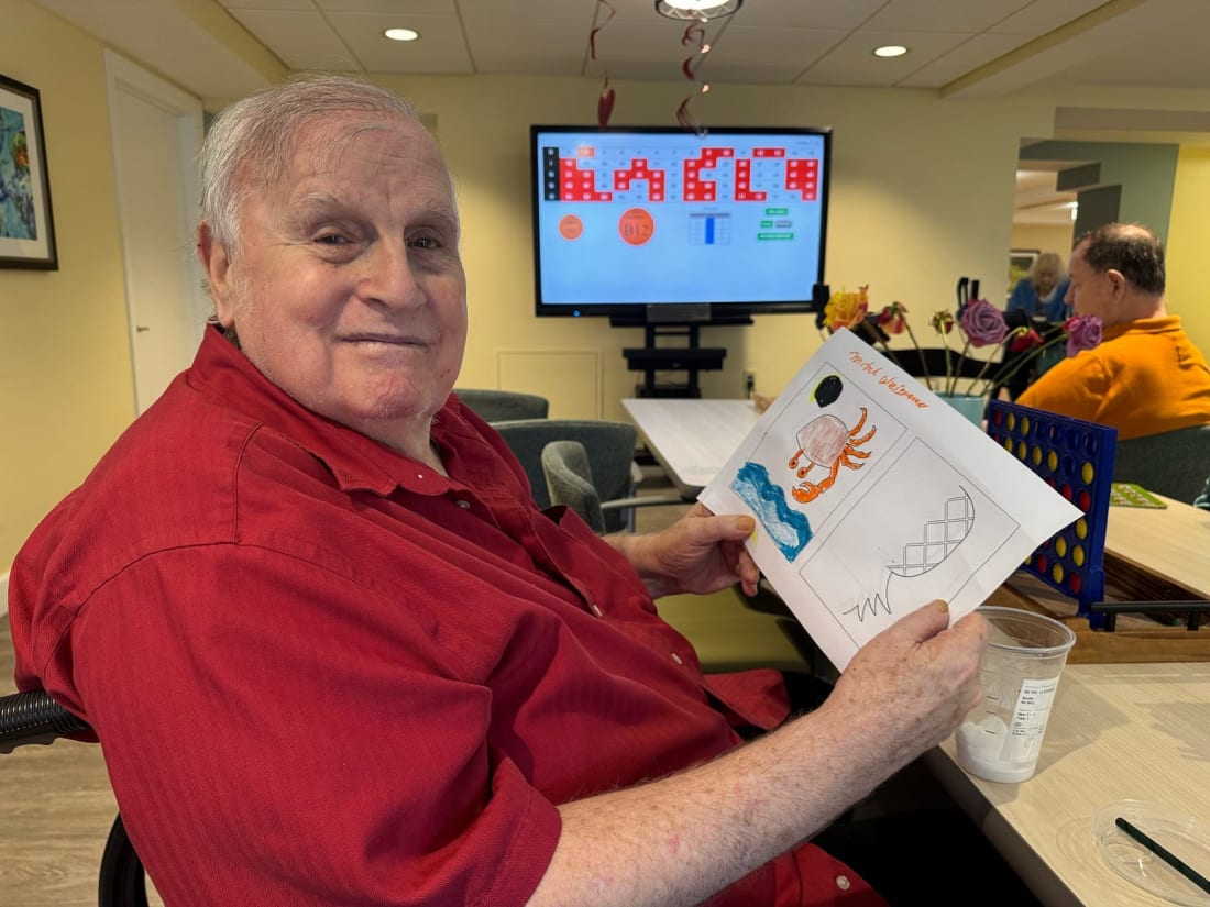 An older man in a red shirt at a memory care center