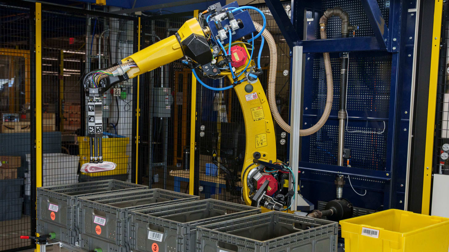 A robotic arm moves products from a bin in an Amazon fulfillment center.