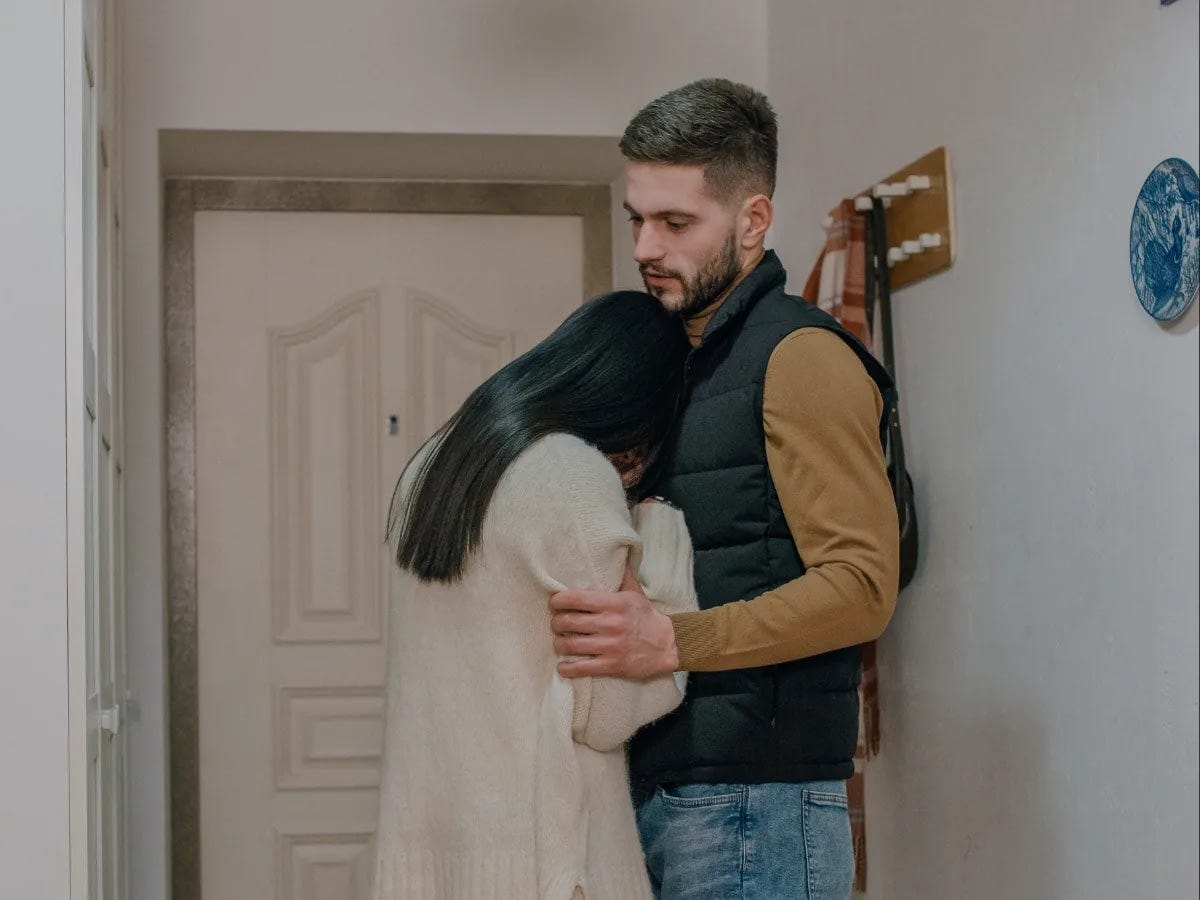 Woman leaning on a man in front of a door.