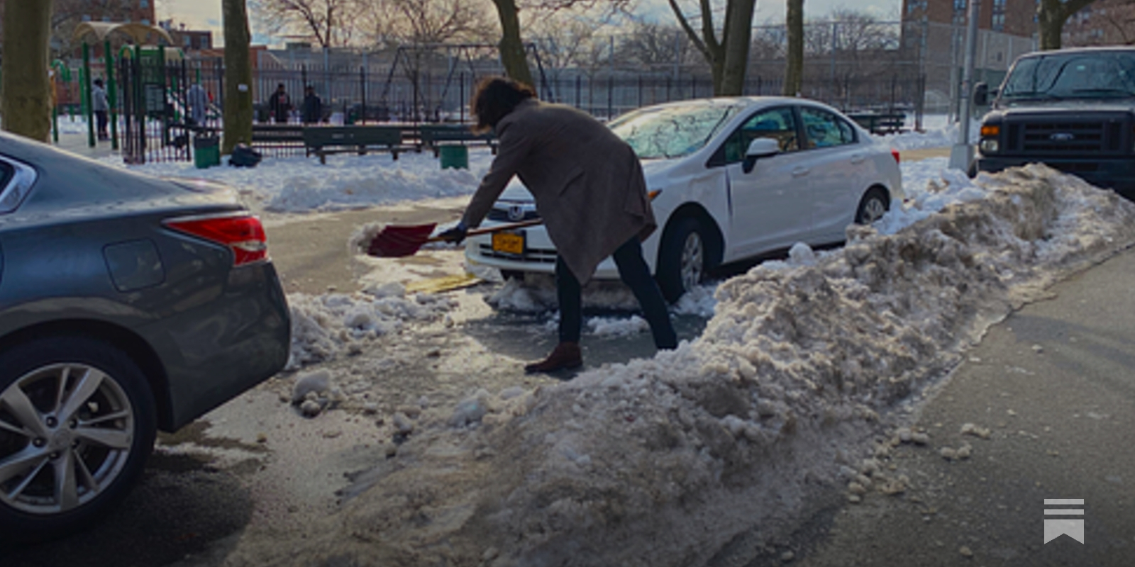 Person shoveling snow near cars