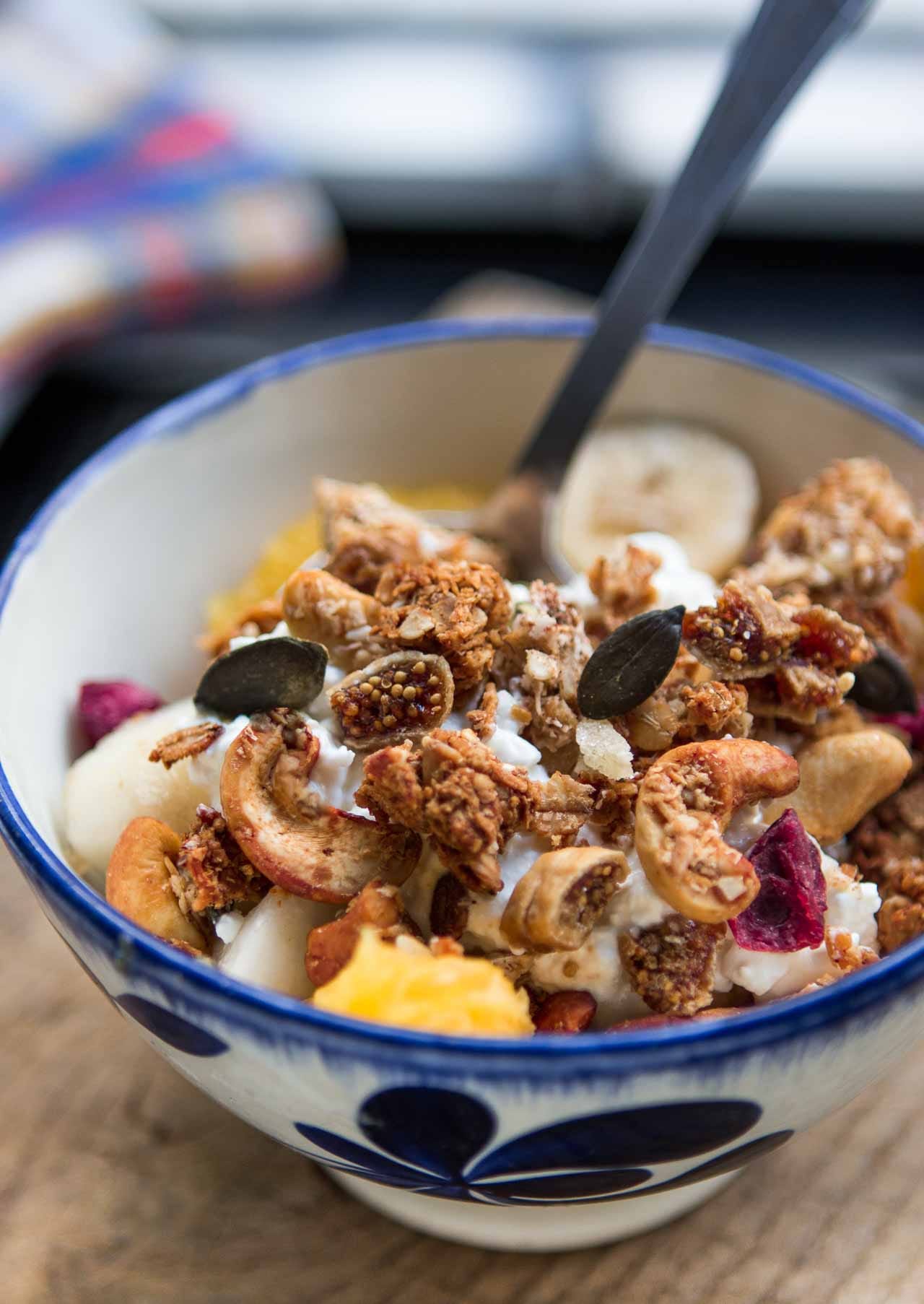 Bowl of cereal with spoon put on wood table near granola in glass