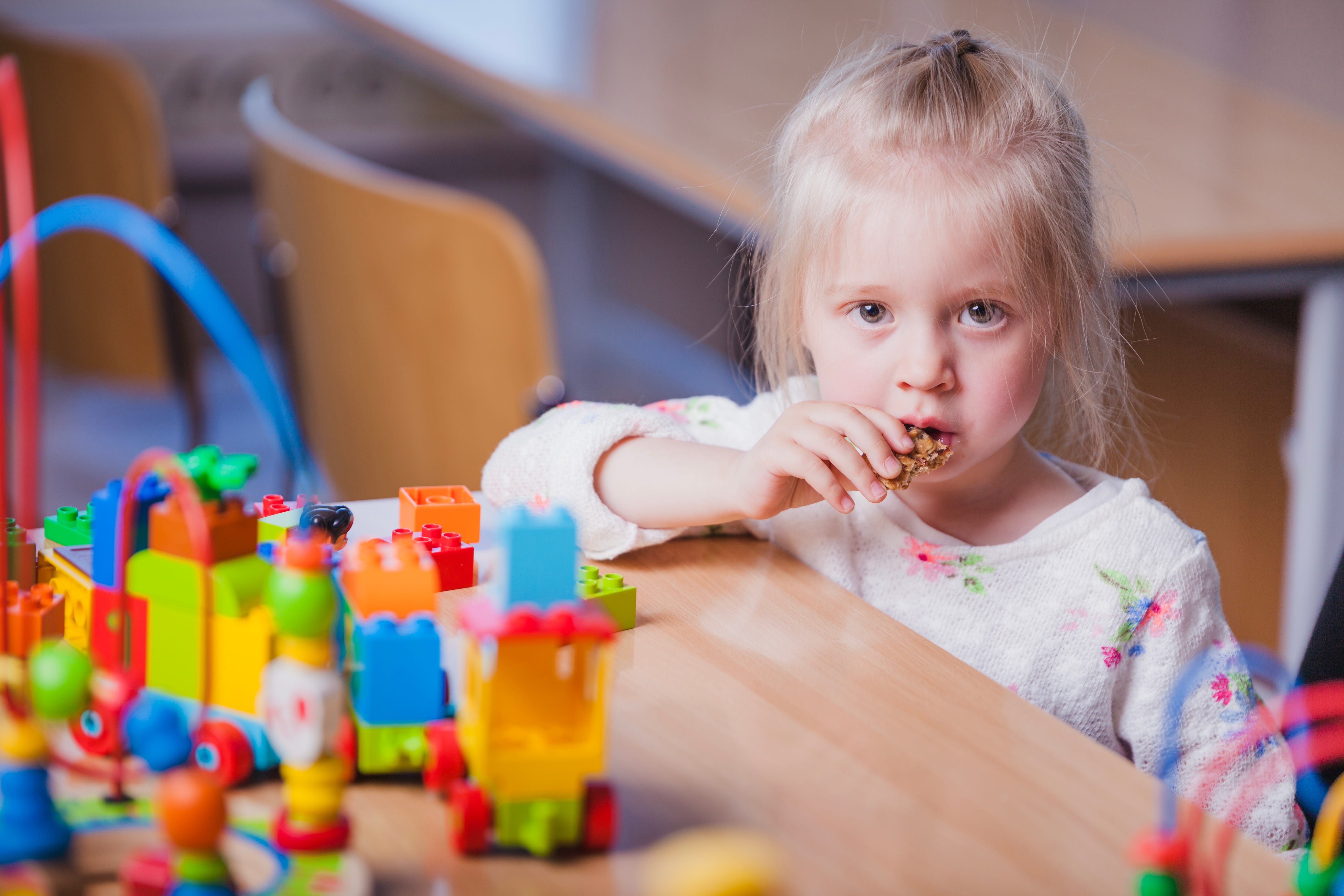 menina numa sala de creche a comer uma bolacha