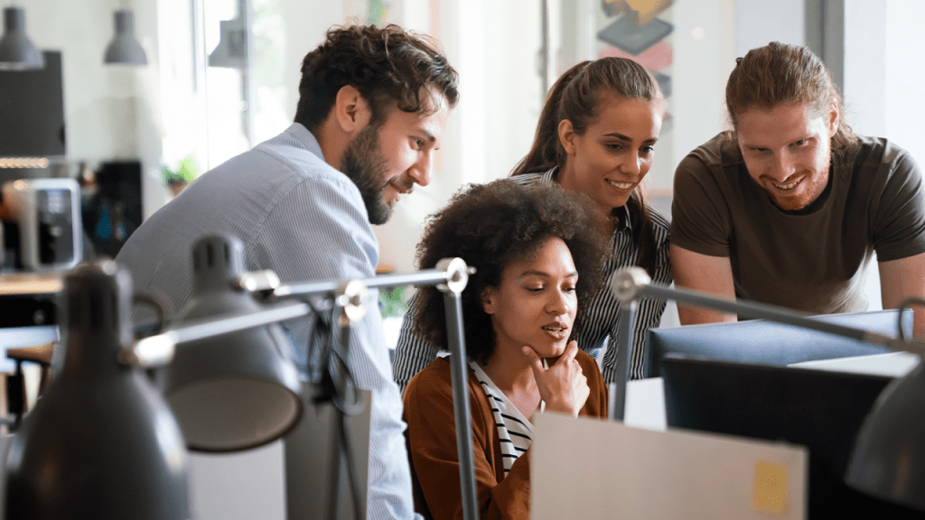 Diverse group of professionals meeting in office. IT programmers use computer, talk strategy