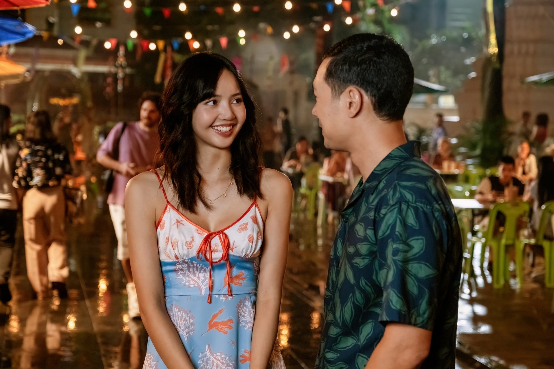 The White Lotus Season 3 Episode 7, Mook and Gaitok on the lively streets of Thailand on their first date. Mook look at gaitok with a stunning smile as he grins back.