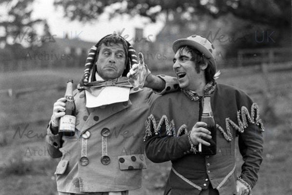 Oliver Reed hands clasped wearing costume as he appears in film