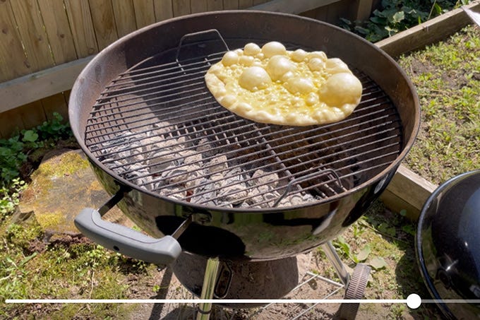 Cooking pizza on charcoal grill top