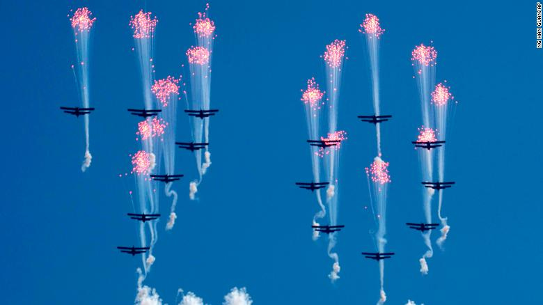 Airplanes forming the number 70 fly in formation and fire flares during the parade.