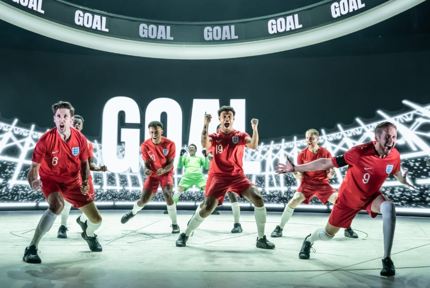 Performers on stage in football kit in a performance of Dear England